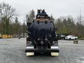 A 2018 Kenworth T800 vacuum truck viewed from the rear with a rounded black tank and multiple hoses and fittings attached to the back