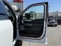 A white 2024 Ford F-550 Super Duty truck with the driver's side door open showing a black interior and door panel