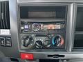 A dashboard of a 2016 Isuzu NPR featuring a digital media player with Bluetooth connection and various control knobs for climate settings