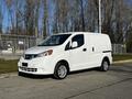 A white 2017 Nissan NV200 van parked on a concrete surface featuring a compact design with sliding side doors and a spacious cargo area