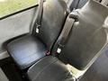 Two black vinyl seats with seatbelts in a bus interior