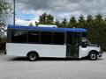 A 2019 Chevrolet Express bus with a blue roof and white body features large windows and double doors in the front for entry and exit