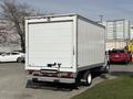 A 2023 Ford E-450 box truck with a white exterior and a rear roll-up door parked in a lot