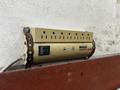 A beige power strip with multiple outlets a power switch and controls for surge protection attached to a wall
