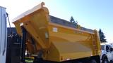 A yellow 2007 Sterling LT8500 dump truck with a raised dump bed and hydraulic lift system