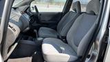 Interior view of a 2006 Honda Fit showing two front seats with light gray fabric and a center console between them