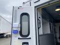 Rear door and interior view of a 2014 Chevrolet Express with emergency equipment mounted on the wall and a partition leading into the main compartment