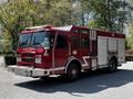 A red 2006 Emergency One fire truck with a front-mounted ladder and multiple compartments for firefighting equipment