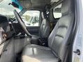 A 2009 Ford Econoline interior showing the driver's seat steering wheel and dashboard with gray leather seats and a console between the front seats