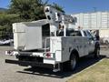 A 2016 Ford F-550 truck with a utility bed and a mounted aerial lift at the rear