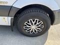 A close-up of a black alloy wheel on a 2010 Mercedes-Benz Sprinter showing a detailed design with silver accents and a rugged tire tread
