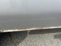 A close-up view of a 2009 Ford Econoline showing its lower body with visible rust along the edge