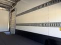 A 2013 Isuzu NPR interior featuring a metal rail system along the walls and a loading dock area on the floor