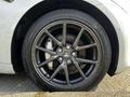 A close-up of a black alloy wheel with a Tesla logo on a 2019 Tesla Model 3 showcasing a sleek design and performance tire