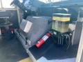 Interior of a 2012 Ford Econoline showing the driver's area with controls and a fire extinguisher mounted on the floor beside an equipment compartment and fluid reservoir