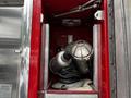 A 1991 Sutphen Deluge fire truck compartment containing two grey firehoses and a light with wires coiled beside it