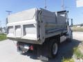 A gray 2005 Freightliner M2 106 Medium Duty truck with a dump bed parked on a road