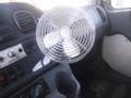 A metal desk fan mounted inside the cabin of a 2005 Freightliner M2 106 Medium Duty truck