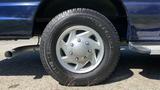 Close-up of a silver alloy wheel and tire from a 2013 Ford Econoline showing detailed tread and five-spoke design