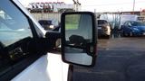 A close-up view of the side mirror of a 2016 Chevrolet Silverado 3500HD showing a black frame and reflective surface with some water droplets