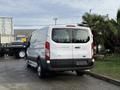 A 2023 Ford Transit van parked with its rear visible showcasing a white exterior and black accents