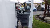 A white 2018 Ford Transit van with the driver's side door open showcasing the interior space and door panel design