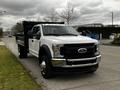 A 2019 Ford F-550 cab and chassis truck in white with a black dump bed parked on a street. The truck features chrome accents and is equipped with dual rear wheels.