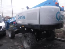 A 2017 Genie S-65 telescopic boom lift with a blue arm and large tires, featuring the Genie logo prominently displayed on its grey body