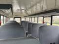 Interior of a 2013 International 3000 school bus featuring grey seats organized in rows with overhead storage and emergency exits visible
