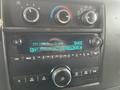 Dashboard of a 2016 Chevrolet Express showing a radio display tuning into FM104.3 with song information and various buttons for audio controls