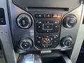 The center console of a 2014 Ford F-150 featuring climate control buttons and radio controls