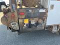 A rusty rear section of a 2007 International 7300 featuring a mounted hook, storage compartment, and warning labels on the side