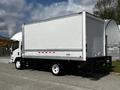 A 2016 Isuzu NQR truck with a large white cargo box and a black flatbed visible at the rear