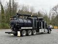 A 2018 Kenworth T800 truck designed for industrial cleaning with a large black tank and multiple hoses attached