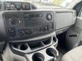 Interior dashboard of a 2010 Ford Econoline featuring controls for audio and climate with cup holders underneath