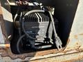A black Genie battery charger with visible wires and a power plug, housed within a rusted compartment of a 2010 SkyJack SJ