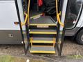Stairs leading into a 2020 Chevrolet Express with yellow handrails and warning signs stating watch your step