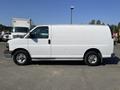 A 2016 GMC Savana van in white color positioned sideways with sliding side door and alloy wheels