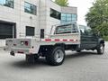 A green 2008 Ford F-550 flatbed truck with a metal bed and rear lights is parked at an angle showcasing its dual rear wheels and extended cab design