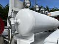 A large white cylindrical tank with frost on its surface and attached valves and pipes visible on a 2016 Ford F-550 truck