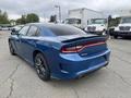 A blue 2022 Dodge Charger is shown from the rear side with a sleek design and tinted windows featuring a distinctive tail light design and sporty rims