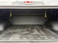 The bed of a 2018 RAM 1500 truck showing a spacious area with a textured floor and four yellow tie-down hooks on the sides