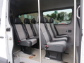 Interior of a 2009 Dodge Sprinter Van featuring rows of fabric-covered seating for multiple passengers with seatbelts attached