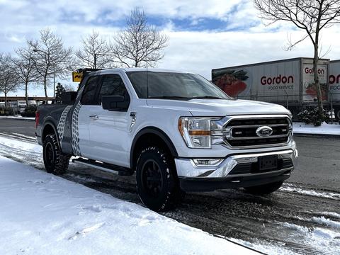 A white 2021 Ford F-150 with a black grille and wheels parked on a snowy street