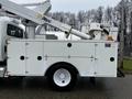 A 2013 International DuraStar white utility truck with a mounted Altec aerial lift and a storage compartment featuring multiple access doors