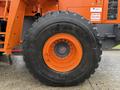 A close-up of a large tire from a 2018 Doosan DL300-5 loader showing an orange rim and deep tread designed for traction on various surfaces