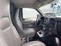 Interior view of a 2014 Chevrolet Express showing two gray front seats dashboard and controls