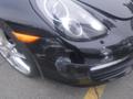 A black 2016 Porsche Boxster with visible scratches and scuffs on the front bumper and side panel