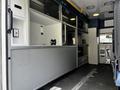 A 2013 Chevrolet Express interior featuring a spacious work area with gray cabinets and several shelves for storage