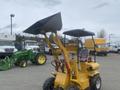 A yellow 2024 AGT KRW 23 mini loader with a raised front bucket and a seat for an operator